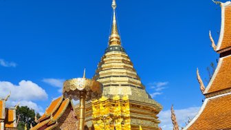 Der goldene Stupa des Wat Phra That Doi Suthep strahlt im Sonnenlicht unter einem klaren blauen Himmel.
