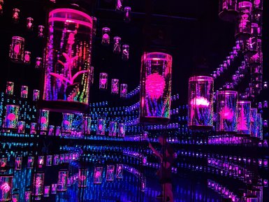 In einem futuristischen Raum hängen leuchtende Glaskapseln mit bunten, pulsierenden Mustern von der Decke.