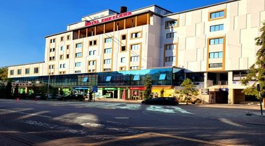 Das moderne Hotel Enkelana in Pogradec zeigt eine helle Fassade mit großen Fenstern und einem einladenden Eingangsbereich.
