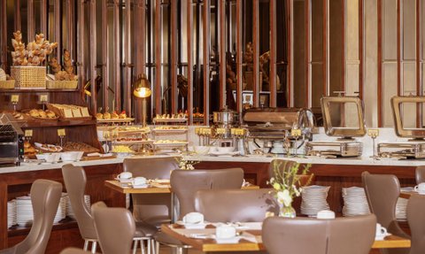 Ein elegantes Restaurant mit Holzregalen, die mit frischen Backwaren und Speisen gefüllt sind, schafft eine einladende Atmosphäre.