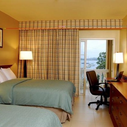 Ein gemütliches Hotelzimmer mit zwei Betten, einem Schreibtisch und Blick auf den Panama-Kanal durch die Fenster.