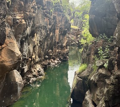 Eine schmale Schlucht mit steilen, zerklüfteten Felsen und klarem, grünem Wasser, das sanft zwischen den Steinen fließt.