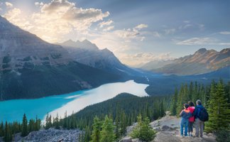 Ein Paar und ein Kind stehen auf einem Aussichtspunkt und bewundern die atemberaubende Landschaft des Icefield Parkway.