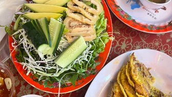 Ein Teller mit knusprigen vietnamesischen Pfannkuchen, umgeben von frischem Gemüse und einer würzigen Sauce.