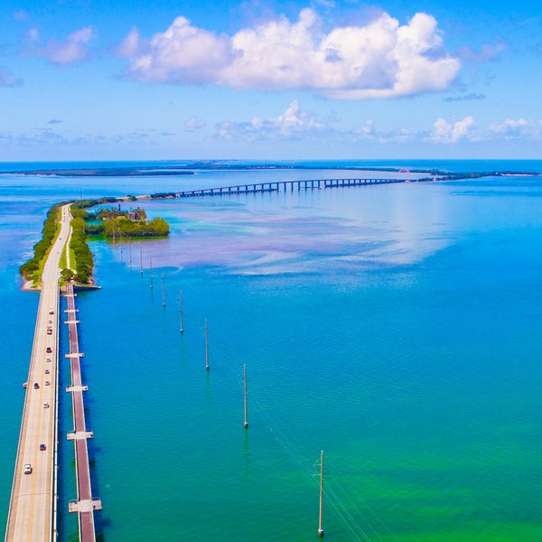 Eine malerische Aussicht auf die lange Brücke, die über das türkisfarbene Wasser von Florida führt, umgeben von üppigem Grün.
