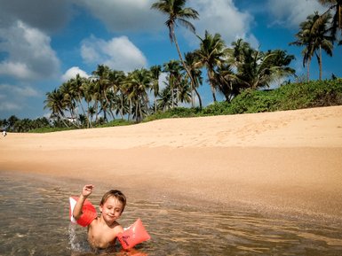 Kleinkind planscht fröhlich im Meerwasser – Sri Lanka Reise mit Kindern