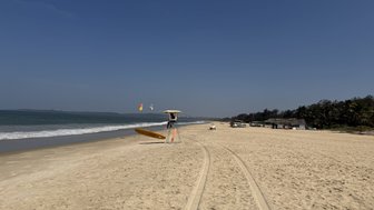 Ein weitläufiger Strand mit sanften Wellen, einem Rettungsboot und einem klaren blauen Himmel, der Ruhe ausstrahlt.