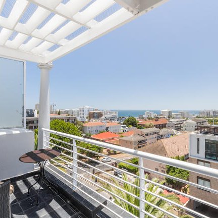 Der Balkon bietet einen atemberaubenden Blick auf die Stadt und das Meer, umgeben von modernen Wohngebäuden.