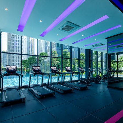 Ein modernes Fitnessstudio mit mehreren Laufbändern, das von großen Fenstern mit Blick auf einen Pool umgeben ist.
