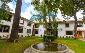Ein malerischer Innenhof mit einem Brunnen, umgeben von einem gepflegten Garten und modernen Gebäuden im Hintergrund.