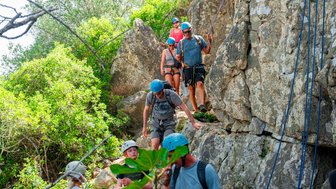 Eine Gruppe klettert mit bewusst gewählten Schritten einen Felsen hinunter