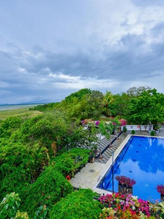 Ein atemberaubender Blick auf einen blauen Pool, umgeben von üppigem Grün und bunten Blumen in einer ruhigen Landschaft.