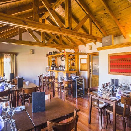 Ein einladendes Restaurant mit Holzbalkendecke, eleganten Tischen und einer gut sortierten Bar im Hintergrund.