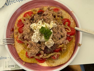 Ein großzügig belegtes Brot mit Thunfisch, frischen Tomaten, Zwiebeln und einer cremigen Schicht Mozzarella in der Mitte.