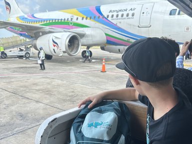Kind mit Rucksack wartet auf Boarding ins Flugzeug - Thailand mit Kindern