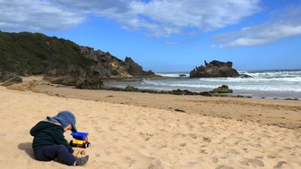 Kleines Kind spielt im Sand am Brenton Beach – Garden Route Reise mit Kindern