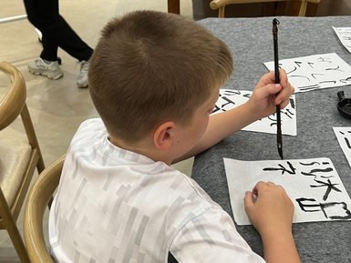Kind schreibt chinesische Schriftzeichen bei einem Kalligrafie-Workshop – China Reise mit Kindern