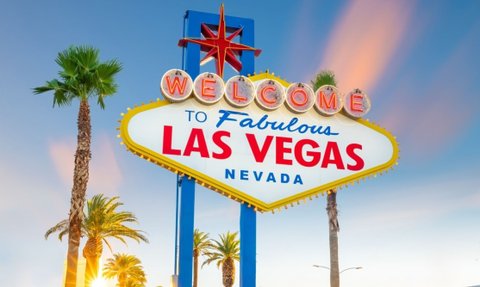 Das berühmte Willkommensschild von Las Vegas strahlt in leuchtenden Farben, umgeben von Palmen und einem klaren Himmel.