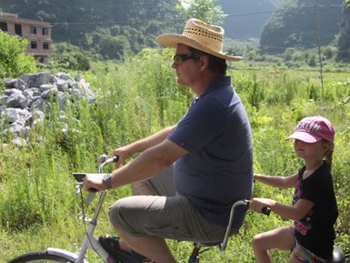Vater und Kind entdecken gemeinsam die Landschaft von Yangshuo auf einer Fahrradtour – China Familienreise
