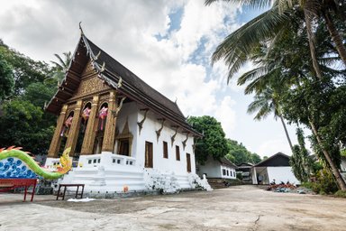 Ein traditioneller buddhistischer Tempel mit kunstvollen Verzierungen und einer bunten Drachenstatue im Vordergrund.