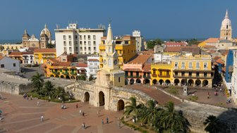 Blick auf die farbenfrohen Gebäude und die historische Architektur in Cartagena, umgeben von Palmen und einem blauen Himmel.