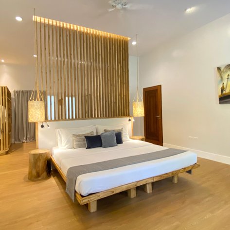Ein modernes Zimmer mit einem großen Bett, Holzdetails und sanfter Beleuchtung schafft eine entspannende Atmosphäre.
