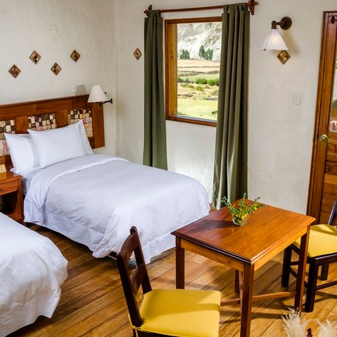 Das gemütliche Zimmer verfügt über zwei Einzelbetten, einen Holztisch und einen Blick auf die umliegende Landschaft.