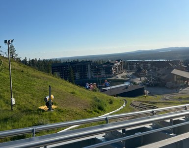 Eine grüne Hügellandschaft mit einem blauen Himmel und einem Blick auf ein Resort in der Ferne, ideal für Freizeitaktivitäten.