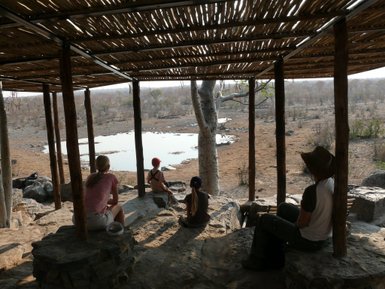 Eine Familie beobachtet im Etosha Nationlpark ein Wasserloch - Namibia mit Jugendlichen