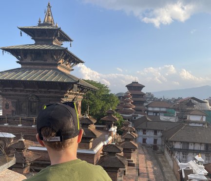 Ein Junge sitzt auf einer Mauer und blickt auf die beeindruckende Architektur der Tempelstadt im Hintergrund.