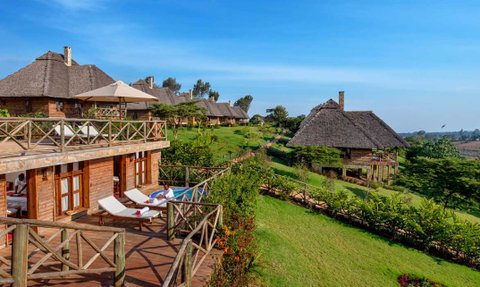 Eine malerische Lodge mit strohgedeckten Dächern, umgeben von üppigem Grün und einem klaren blauen Himmel.