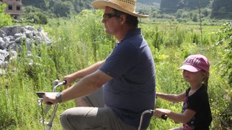 Vater und Kind entdecken gemeinsam die Landschaft von Yangshuo auf einer Fahrradtour – China Familienreise