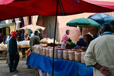 Auf einem Markt vertreibt ein Verkäufer verschiedene Snacks und Gebäck, während die Kunden interessiert zuschauen.
