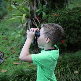Junge beobachtet die Tierwelt mit Fernglas bei der Maquenque Eco Lodge im Sarapiquí-Tal – Costa Rica Reise mit Kindern