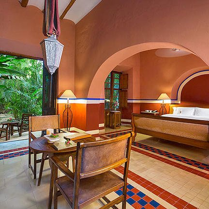 Ein elegantes Hotelzimmer mit warmen, erdigen Farbtönen, einem großen Bett und Blick auf einen üppigen Garten.