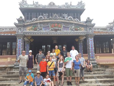 Eine Gruppe von Touristen posiert vor der kunstvoll verzierten Thien Mu Pagode in Hue, umgeben von historischen Details.