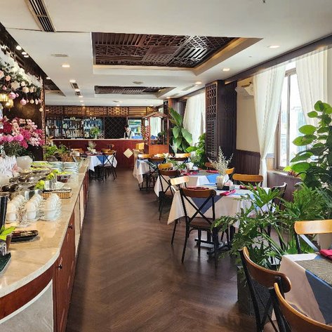 Ein elegantes Restaurant mit geschmackvoll gedeckten Tischen und üppigen Pflanzen, das eine einladende Atmosphäre schafft.