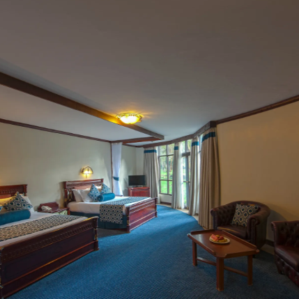 Ein elegantes Hotelzimmer mit zwei Betten, blauen Akzenten und einem gemütlichen Sitzbereich mit einem Tisch.