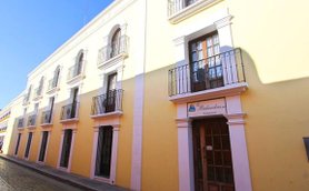 Eine gelbe Gebäudeansicht mit mehreren Fenstern und Balkonen, die eine einladende Atmosphäre ausstrahlt.