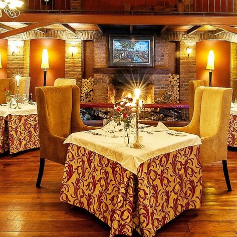 Ein elegantes Restaurant mit warmem Licht, gemütlichen Stühlen und einem einladenden Kamin im Hintergrund.