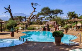 Ein einladender Pool in der Kenia-Amboseli-Region, umgeben von üppiger Vegetation und Blick auf den majestätischen Kilimandscharo.