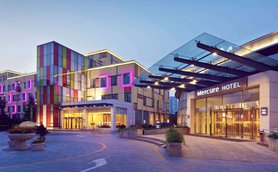 Das Mercure Hotel in Peking zeigt eine moderne Architektur mit bunten Fassaden und stilvollen Lichtern in der Dämmerung.