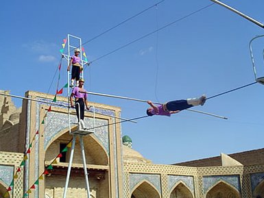 Drei Akrobaten führen eine beeindruckende Seiltanz-Performance in einem historischen, architektonisch reichen Umfeld auf.