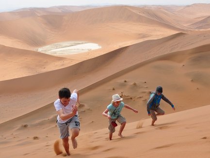 Drei Kinder laufen eine Düne hinauf - Namibia Rundreise mit Kindern