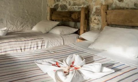 Ein gemütliches Doppelzimmer mit zwei Betten, rustikalen Holzmöbeln und einer kunstvollen Wanddekoration.