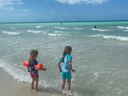 Kinder planschen am Ufer und schauen auf das Meer – Mexiko mit Kindern