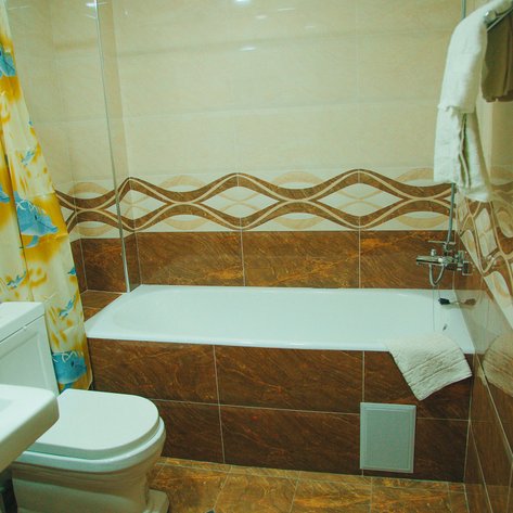 Ein modernes Badezimmer mit einer Badewanne, einer Toilette und einem Waschbecken, umgeben von eleganten Fliesen.