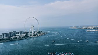Ein atemberaubender Blick auf Ain Dubai, das größte Riesenrad der Welt, umgeben von strahlend blauem Wasser und modernen Gebäuden.