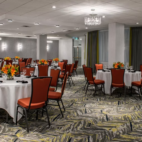 Elegante Restaurantatmosphäre mit runden Tischen, die mit bunten Blumenarrangements und Gläsern dekoriert sind.