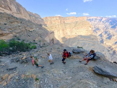 Familie erkundet zu Fuß die beeindruckende Berglandschaft und Felsformationen des Jebel Shams – Oman Familienreise